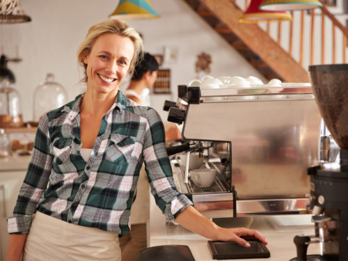 Lächelnde Frau in einem Café oder Restaurant, die das Kassensystem Yoveletta verwendet.