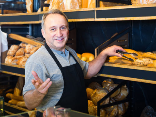 Ein Bäcker lächelt in die Kamera und nutzt Yoveletta, das Kassensystem für Bäckerei und Konditorei.